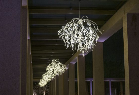 Hangingn white lit chandeliers over an outdoor walkway.